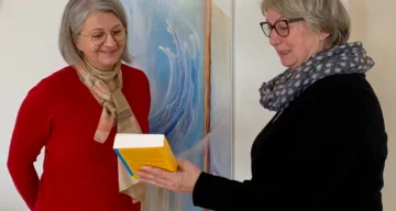 Maria Huber übergibt Margarete Steiner ein Wesley Brevier als Willkommensgeschenk im Gottesdienst mit Taufbekenntnis und feierlicher Aufnahme, 10.12.2022 in Ried