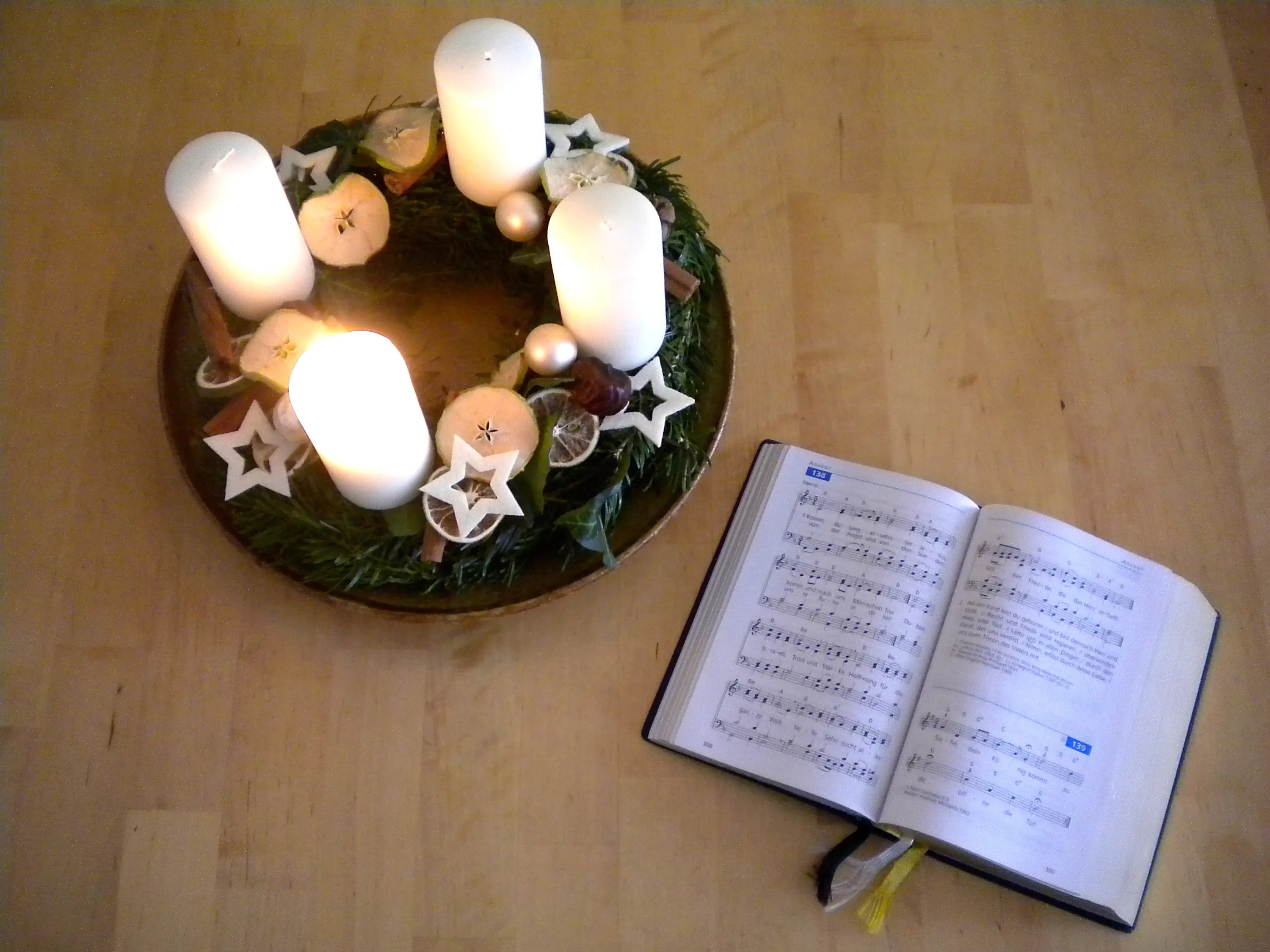 Anregungen für den Advent Adventkranz mit entzündeter 1. Kerze und Gesangbuch EM aufgeschlagen bei Lied 138 "Komm, du lang ersehnter Jesus"