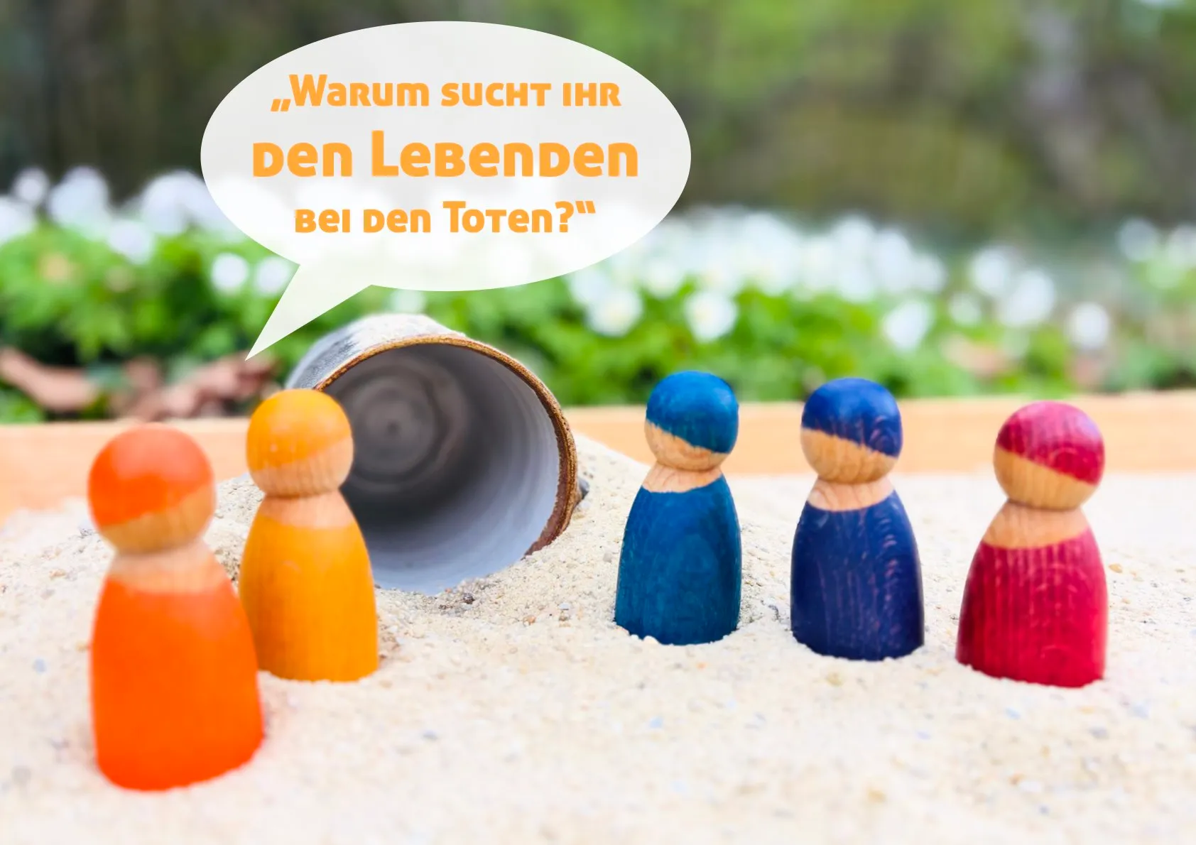 Bunte Holzfiguren auf Sand vor dem leeren Grab. Die leuchtenden Figureb fragen: "Warum sucht ihr den Lebenden bei den Toten?" (Lukas 24,5)