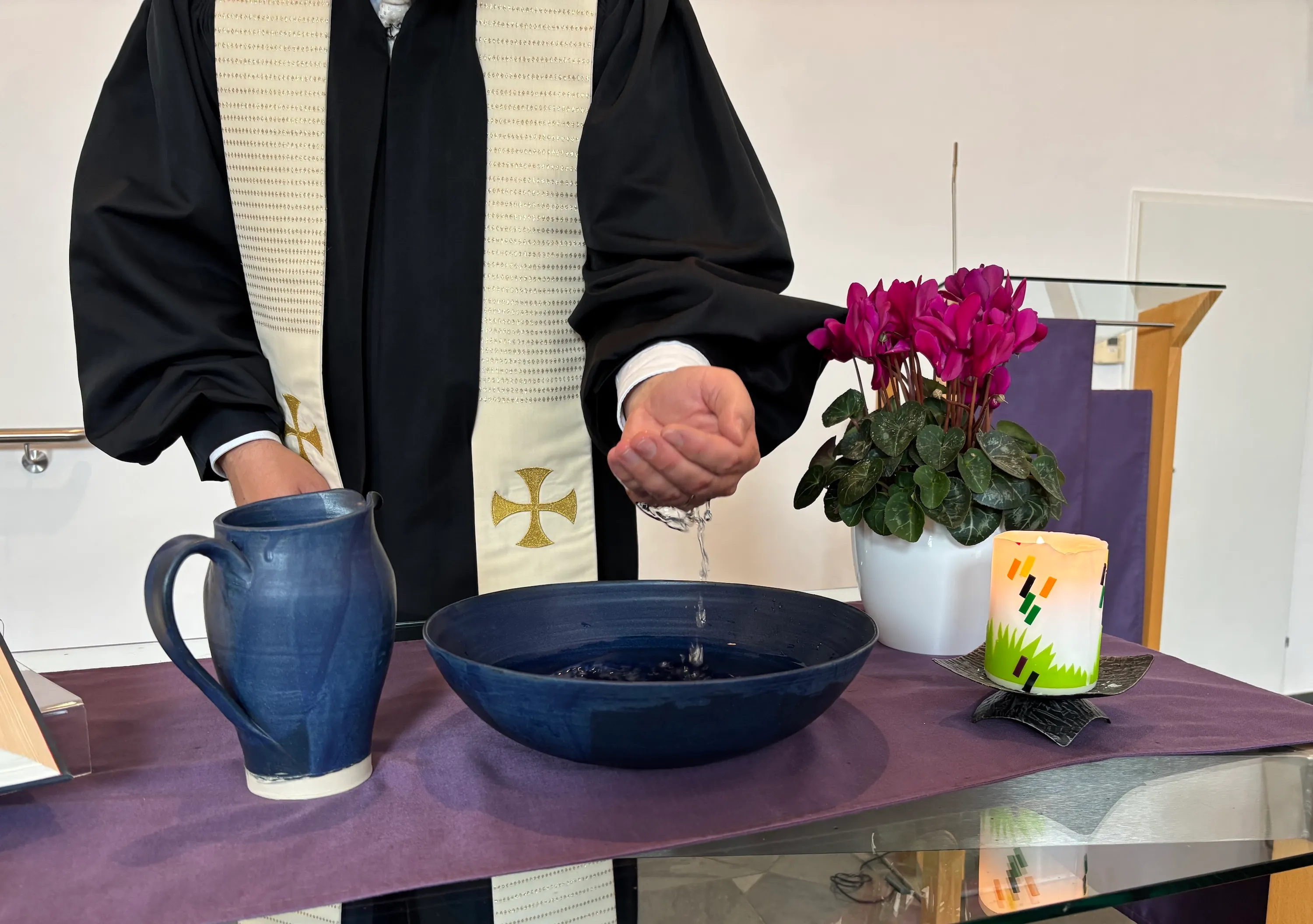 Pastor Martin Obermeir-Siegrist schöpft in der EmK Linz Wasser aus dem Taufbecken.