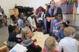 Kinder sitzen mit dem Pastor am Boden