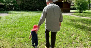 Kind und Erwachsener Hand in Hand auf einer Wiese